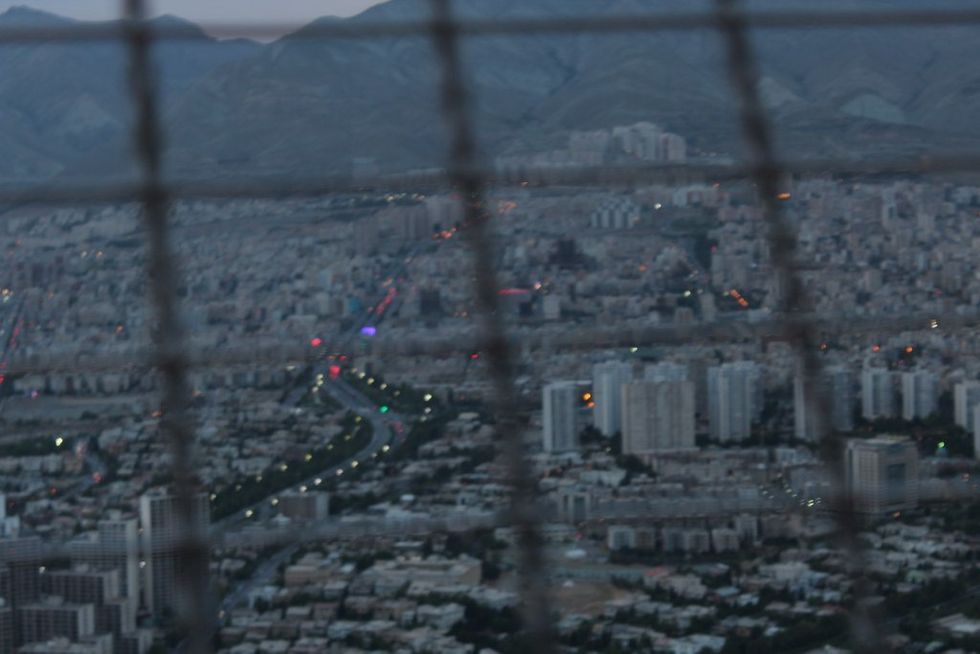 Photo of the Tehran cityscape, shot through a fence