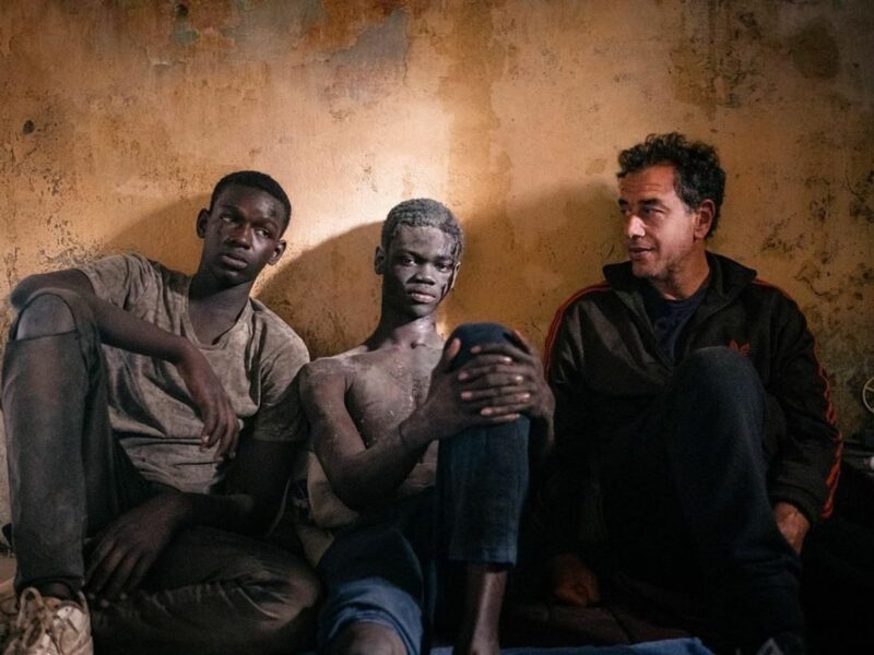 photo of three men sitting against a wall