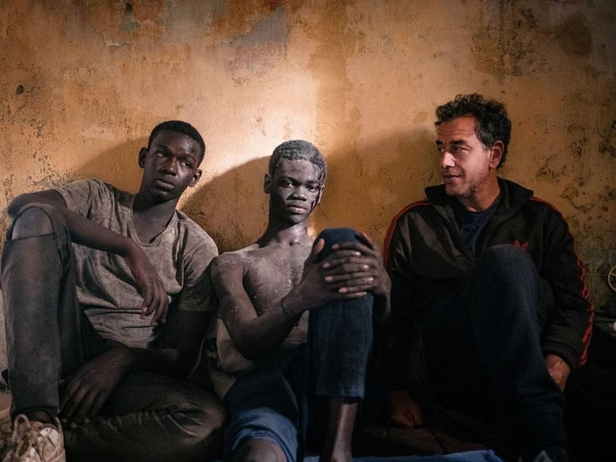 photo of three men sitting against a wall