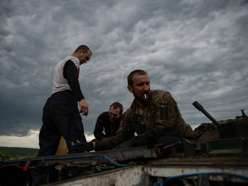photo of three men working on a tank