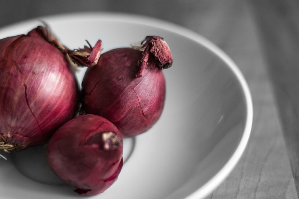 Photo of three red onions on a plate