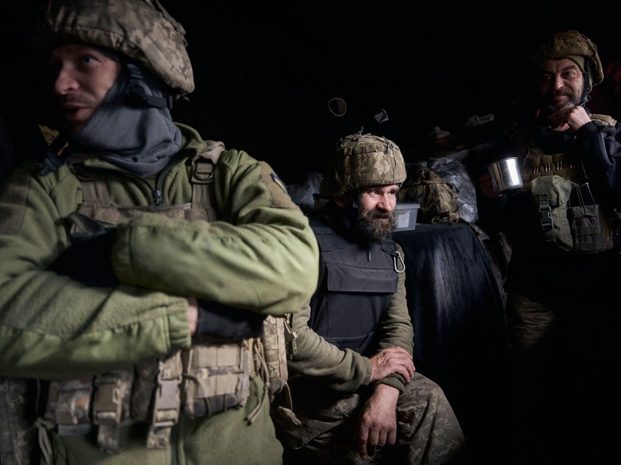 Photo of three Ukrainian soldiers in military gear, waiting on the frontlines,
