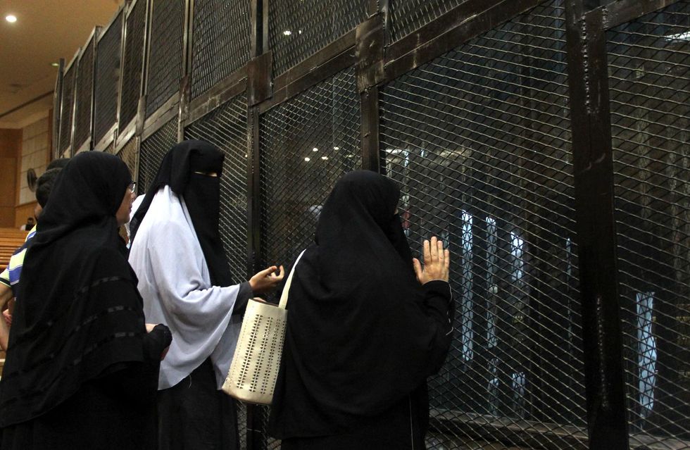 Photo of three women speaking with imprisoned defendants at a Cairo court