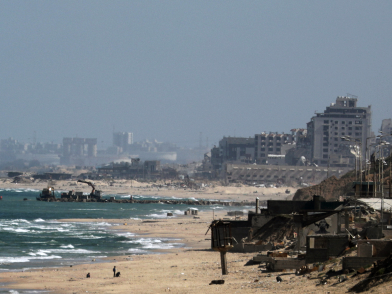 Photo of trucks transporting heavy equipment and large cement blocks for use in constructing a new pier on the Gaza City seashore.
