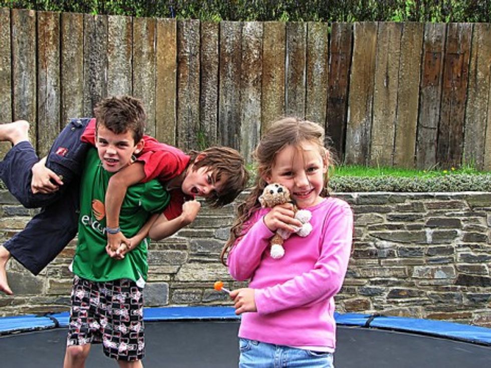 Photo of two boys and a girl playing on a trampoline