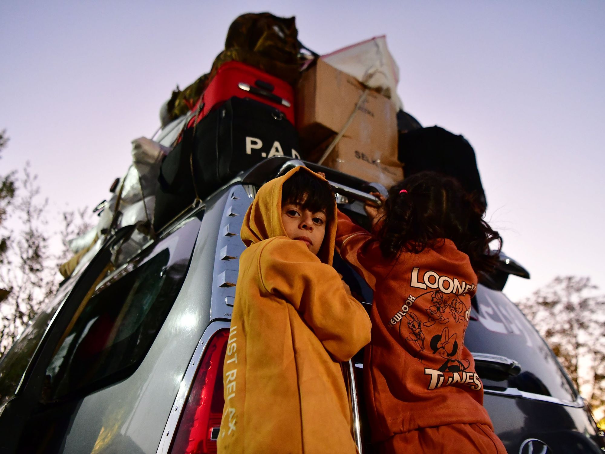 Photo of two children putting their belongings in a car as people flee from Lebanon into the Syrian countriside at the Jdeidat Yabous border crossing on Sept. 24.
