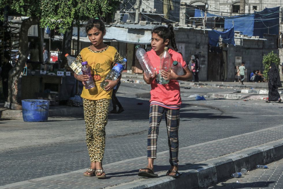 Photo of two girls in Gaza carrying water bottles