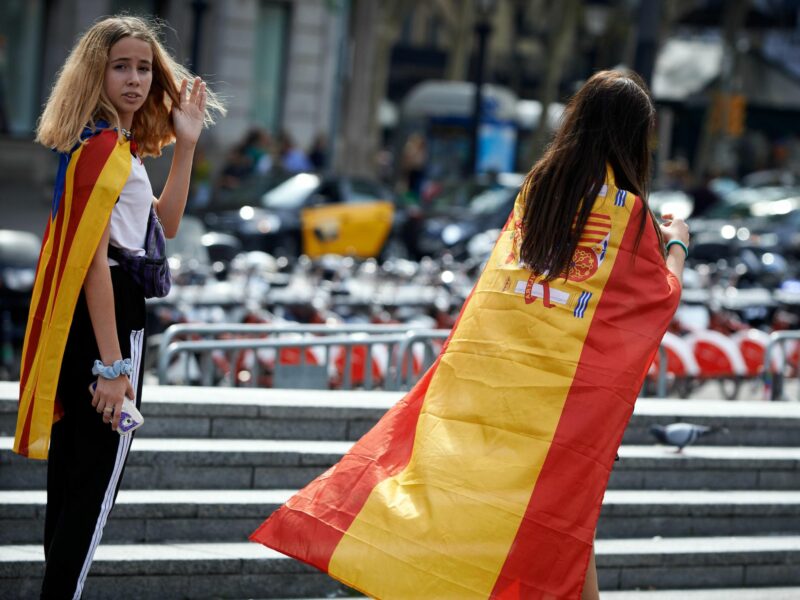 Photo of two girls wearing Catalan and Spanish flags in Barcelona, Spain