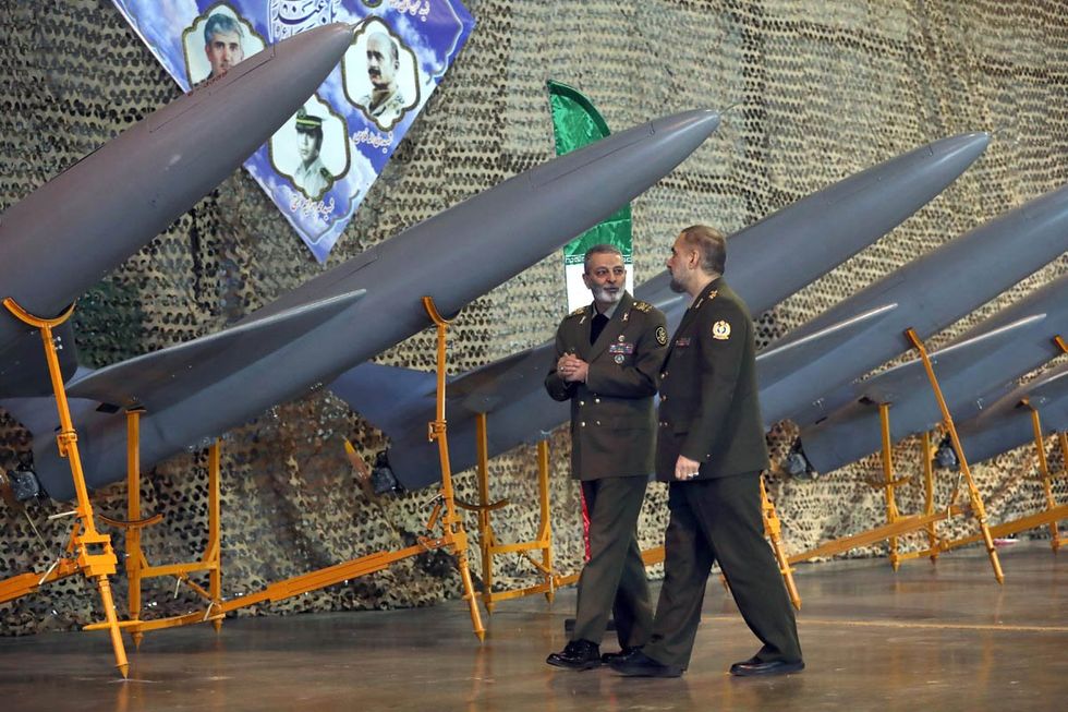 photo of two men in uniform in front of missiles