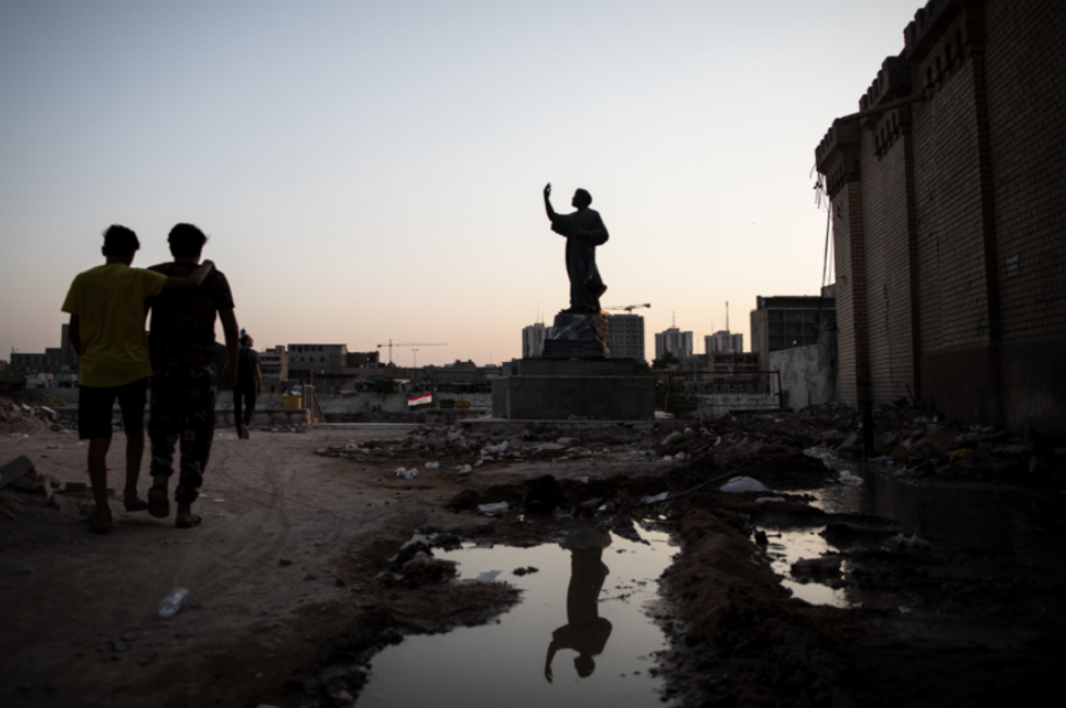 Photo of two men walking on Al-Mutanabbi street, in the historic centre of Baghdad, near the statue of Arab poet Al-Mutanabbi