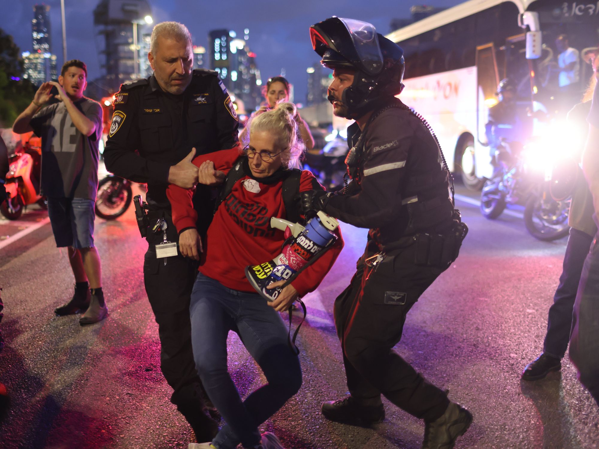 photo of two police moving a protester in a red shirt