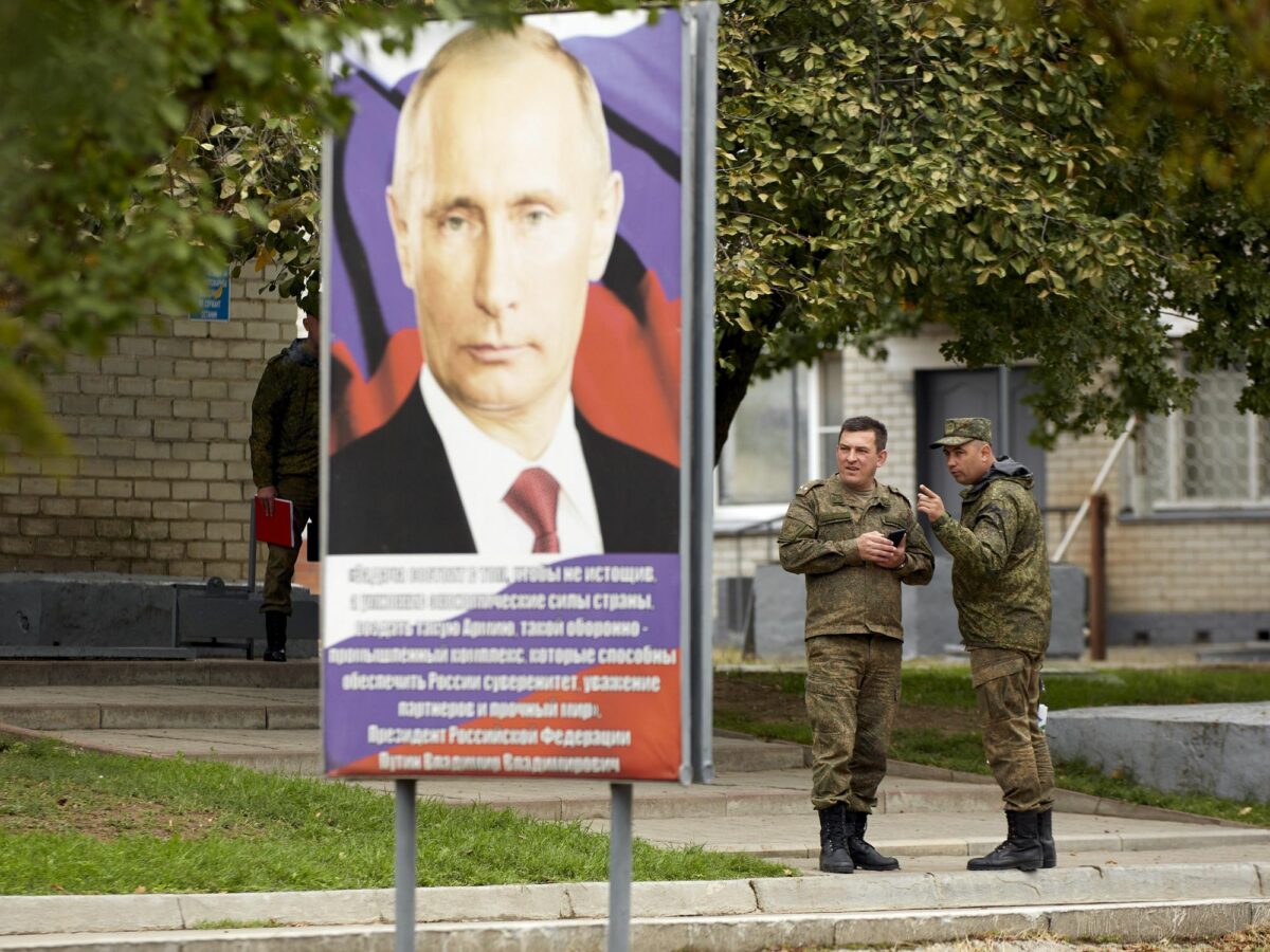 Photo of two soldiers standing by a poster featuring Russian President Vladimir Putin in Stavropol, Russia