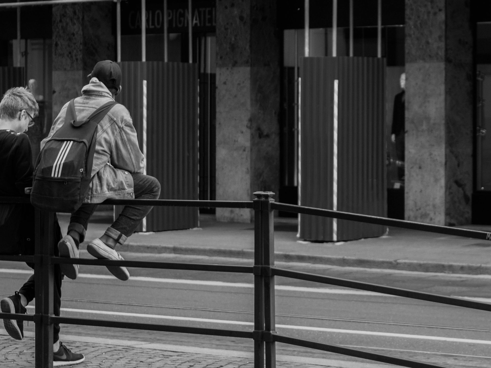 Photo of two teenagers sitting on a rail.