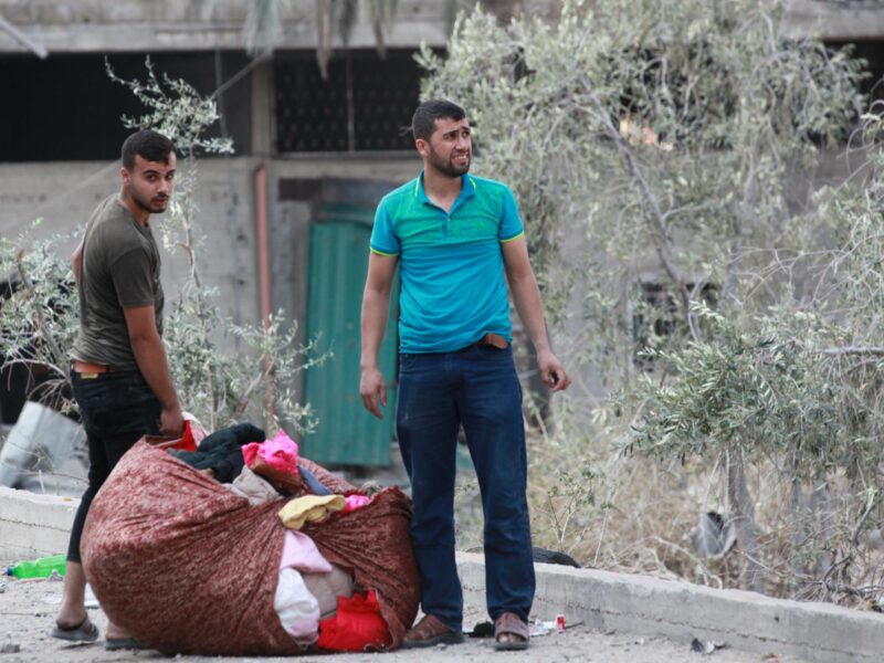 photo of two young man carrying their possessions in a sheet