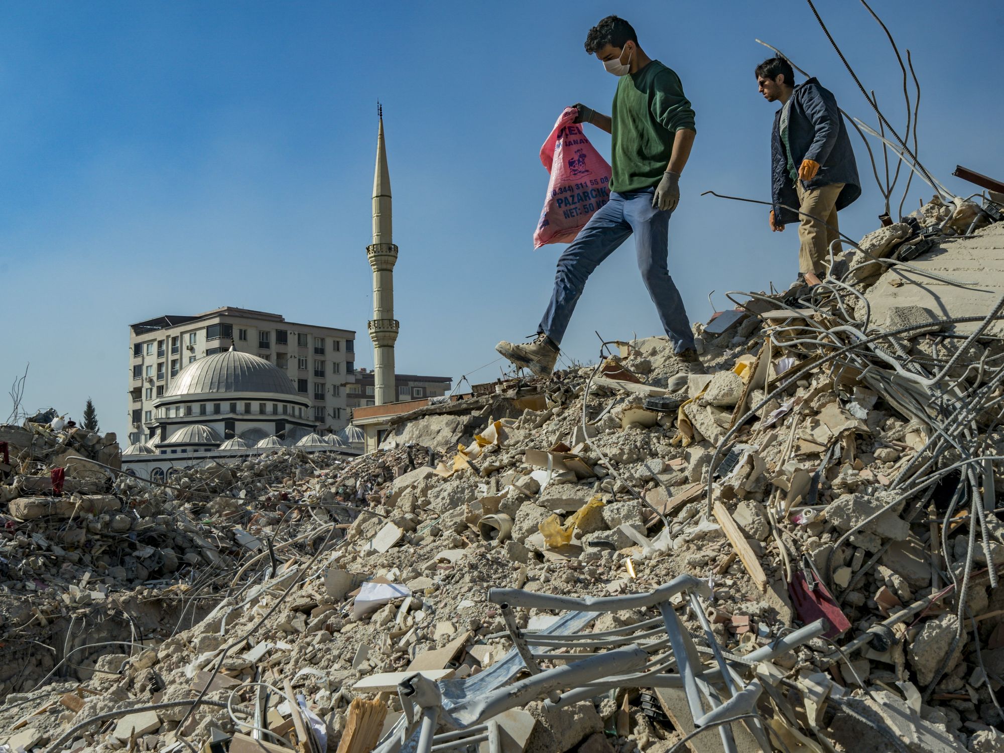 Photo of two young people in Kahramanmarash, Turkey, look for their belongings in the debrish of their homes destroyed by the earthquake.