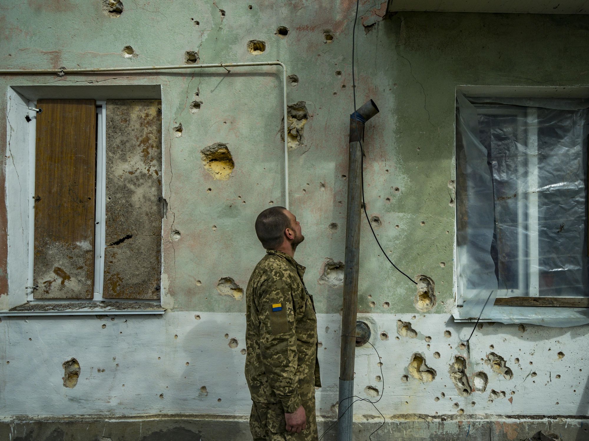 Photo of Ukrainian soldier looking at the destruction in a wall