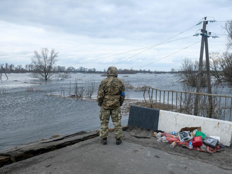 Photo of Ukrainian soldier standing near a destroyed bridge.