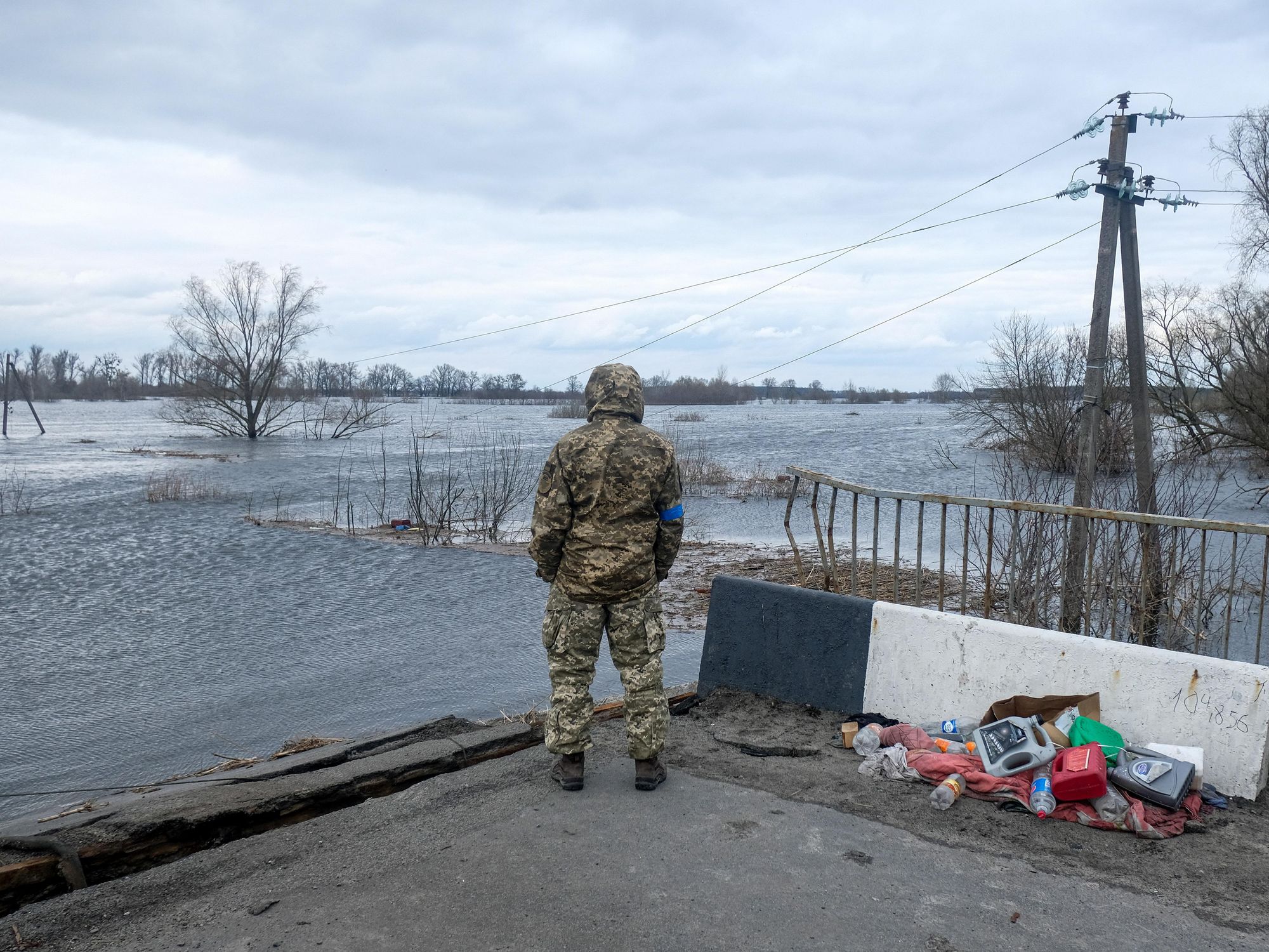 Photo of Ukrainian soldier standing near a destroyed bridge.