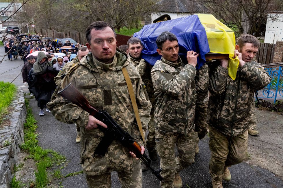 Photo of Ukrainian Soldiers acting as pall bearers as the coffin of Artur Asadov is transported to the cemetery in Pidhirtsi.
