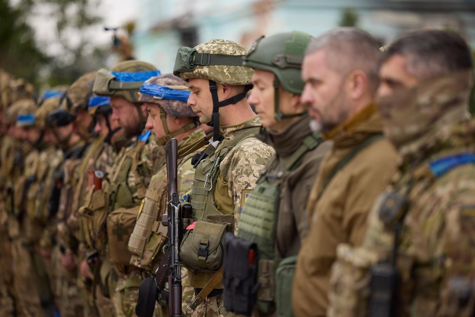 Photo of Ukrainian soldiers in military gear, lined up as they attend a flag raising ceremony in Izyum.