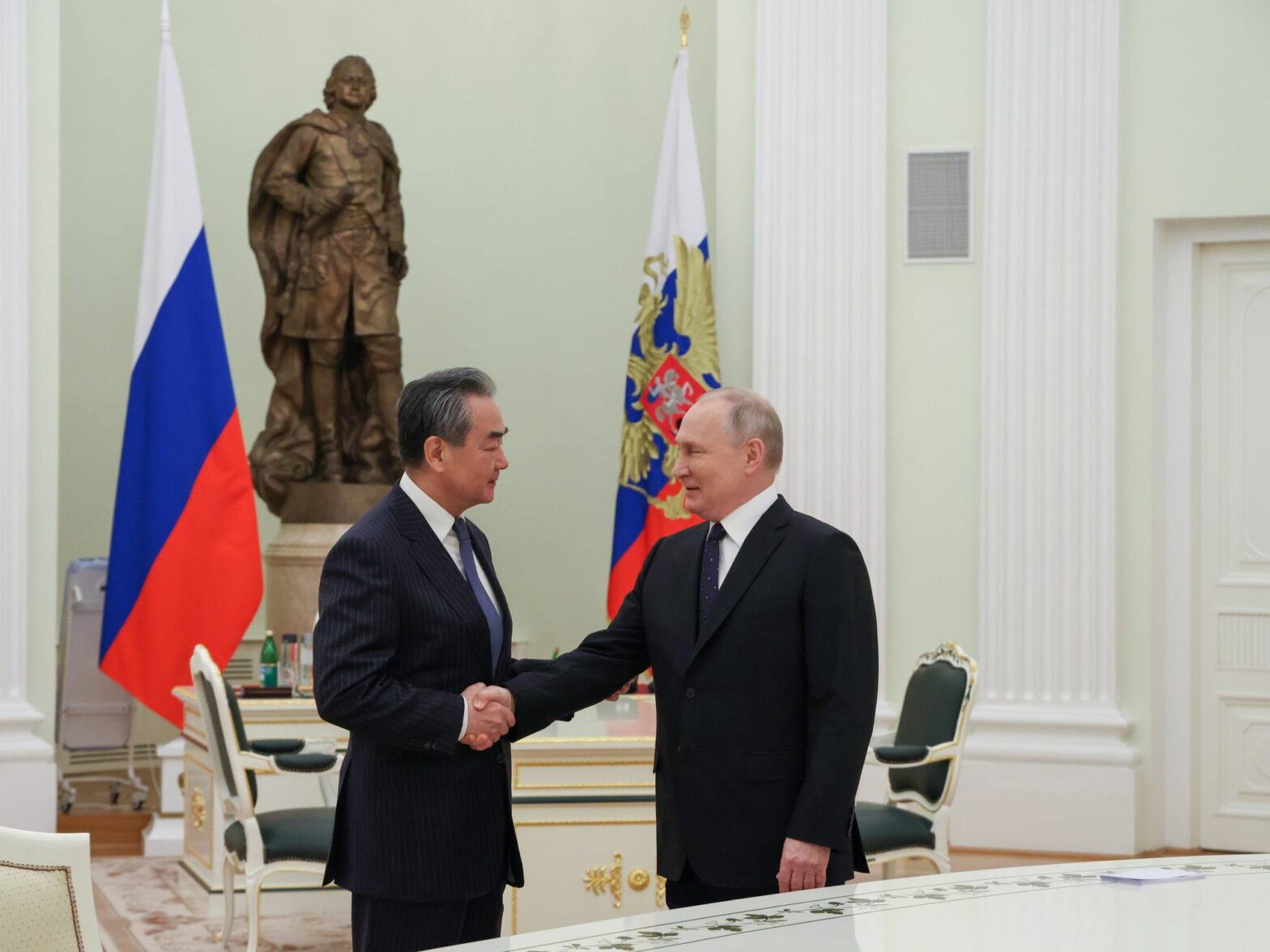 Photo of Vladimir Putin shaking hands with head of Chinese diplomacy Wang Yi at the Kremlin