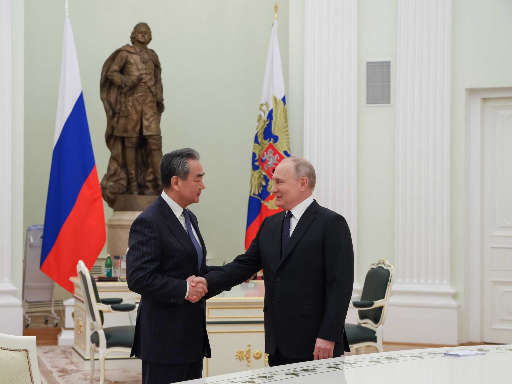 Photo of Vladimir Putin shaking hands with head of Chinese diplomacy Wang Yi at the Kremlin