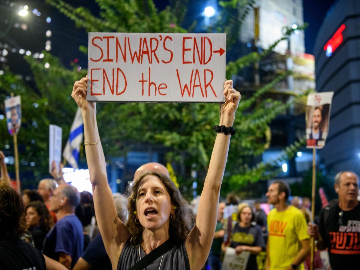photo of woman holding up poster to end war in gaza