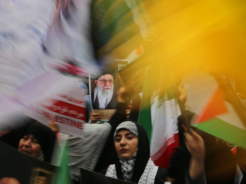 photo of women holding iranian and palestinian flags and photo of supreme leader Ayatollah Khamenei