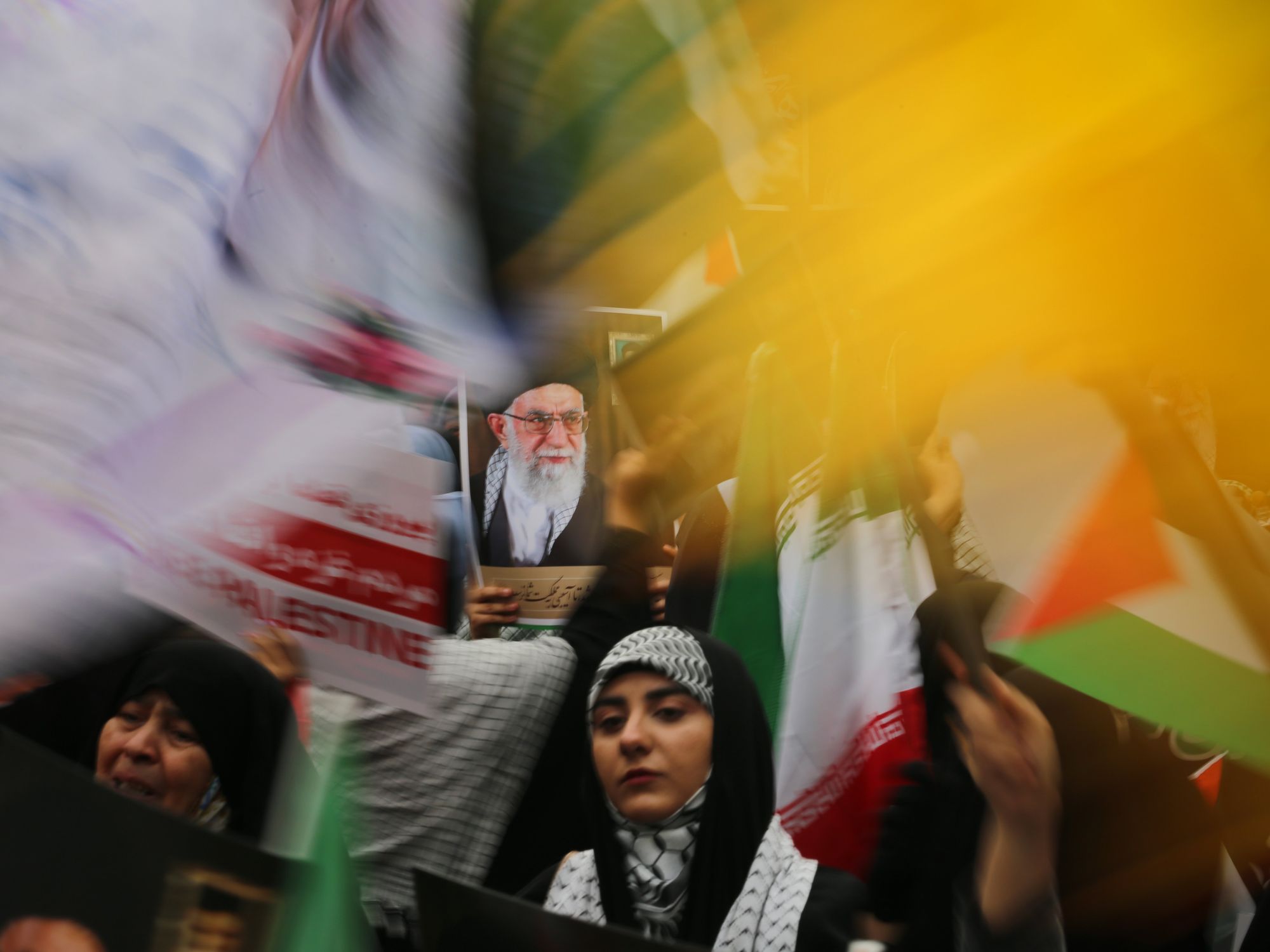 photo of women holding iranian and palestinian flags and photo of supreme leader Ayatollah Khamenei