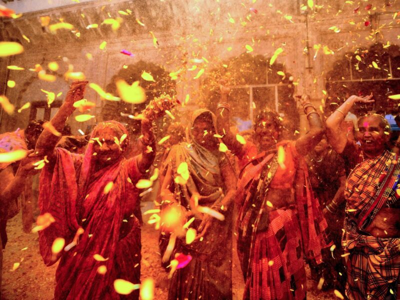 Photo of women throwing petals and colored powders as part of ​Holi celebrations in Vrindavan, India, on March 15
