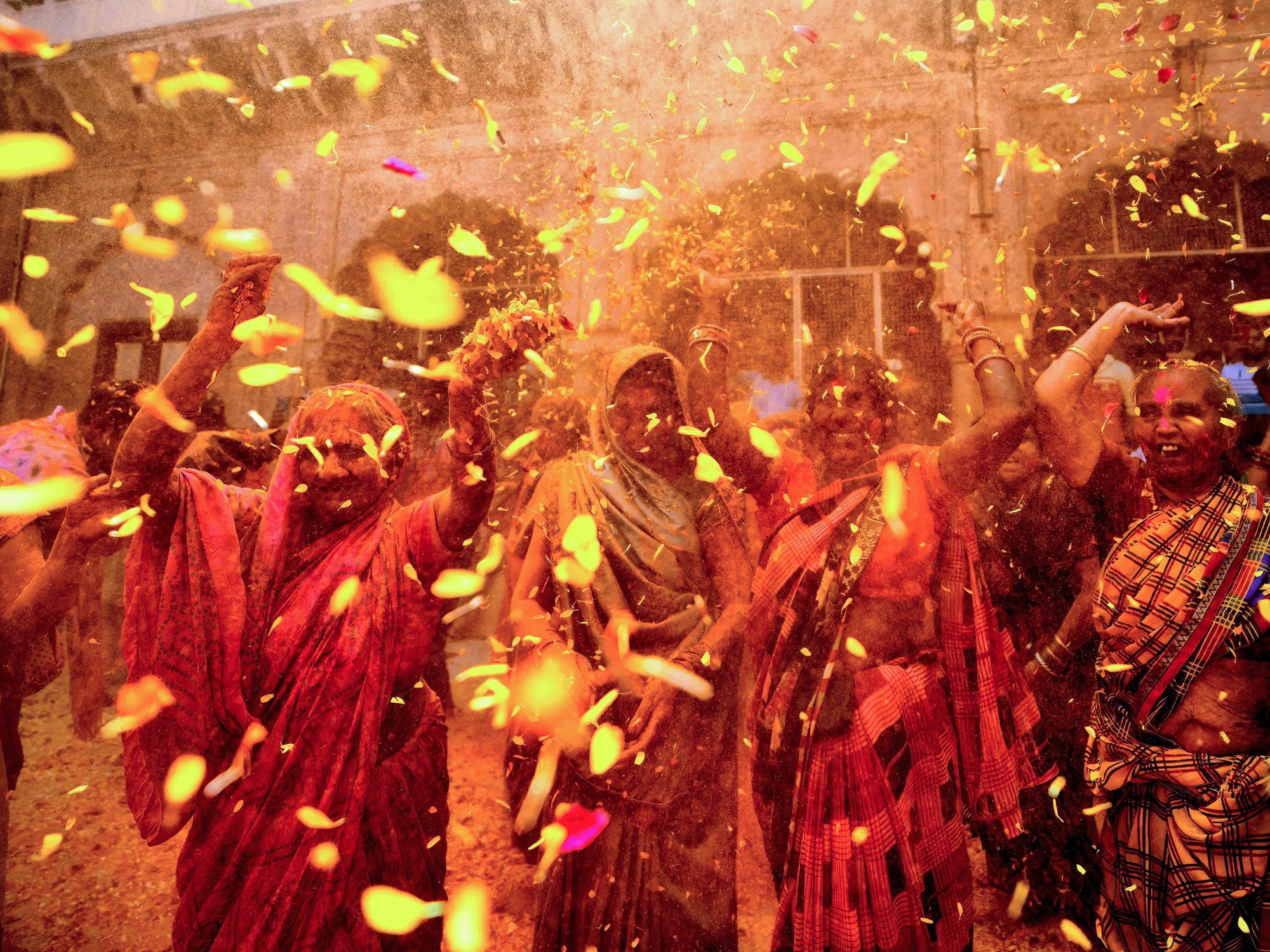 Photo of women throwing petals and colored powders as part of ​Holi celebrations in Vrindavan, India, on March 15