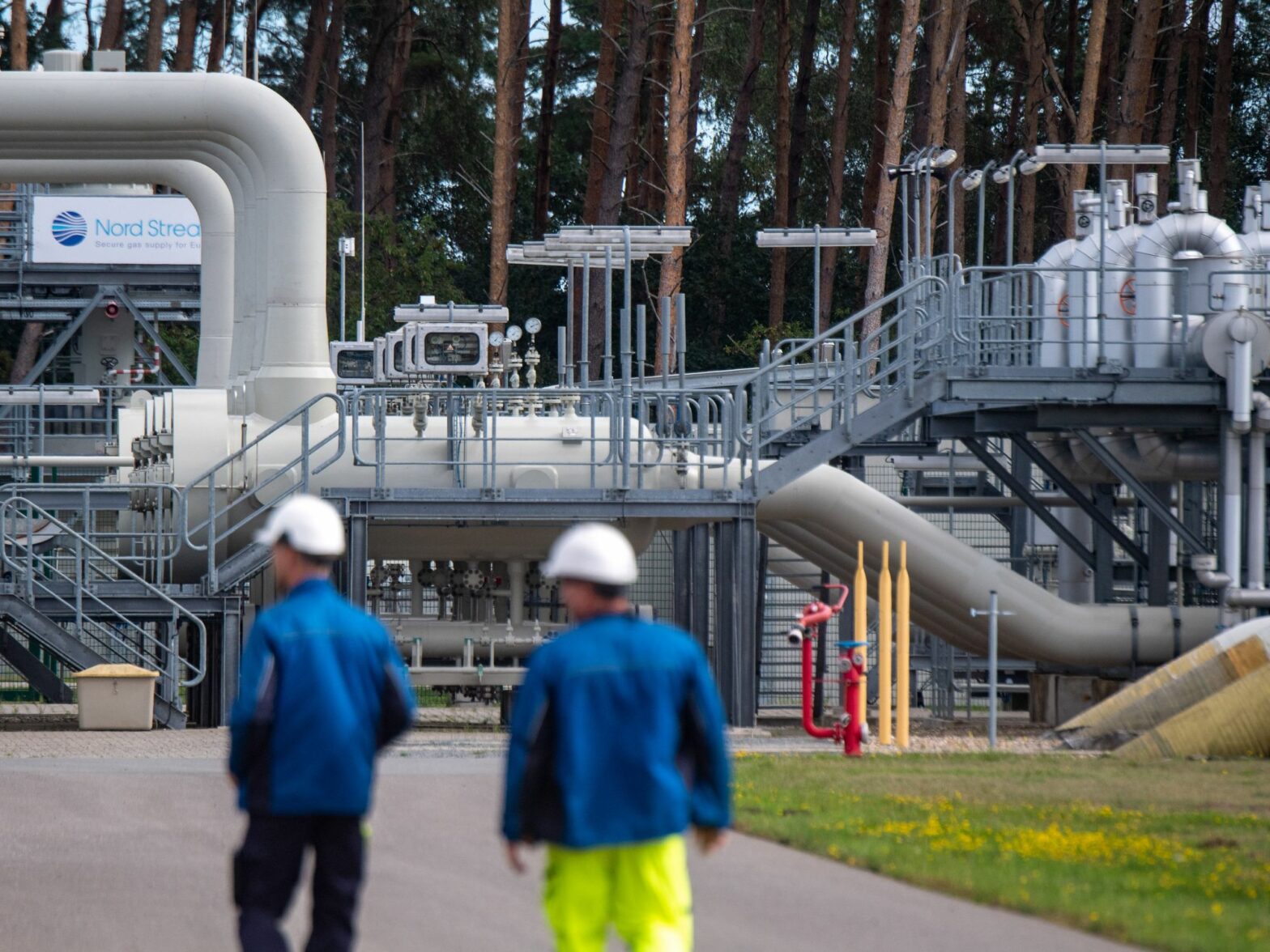 Photo of workers walking by a receiving station for the Nord Stream 1 Baltic Sea pipeline in Lubmin, Germany