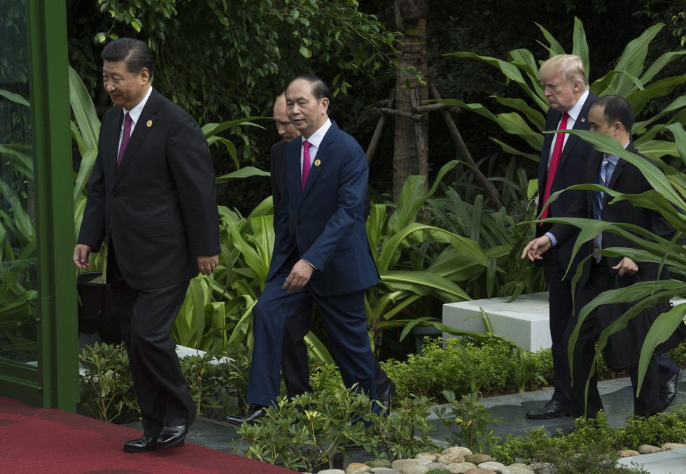 photo of Xi walking in front of Trump