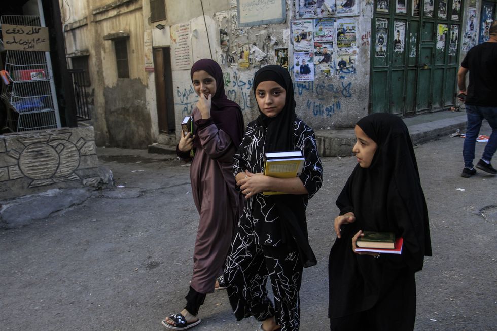 Photo of young children carrying books in Palestine.