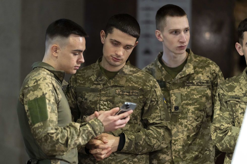 photo of young soldiers looking at a smartphone