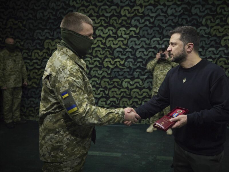 photo of zelensky shaking hand with a soldier who is covering his face