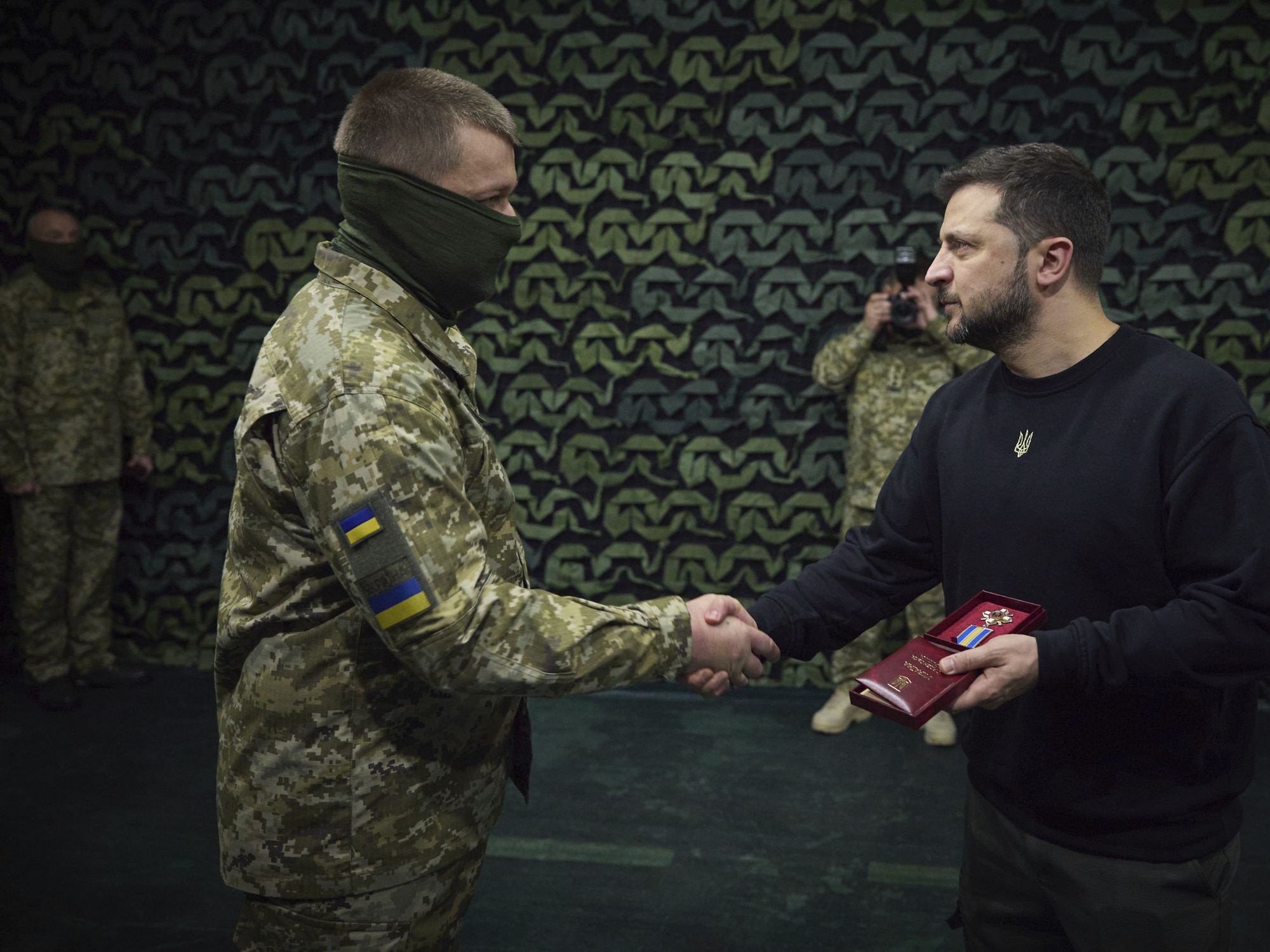 photo of zelensky shaking hand with a soldier who is covering his face