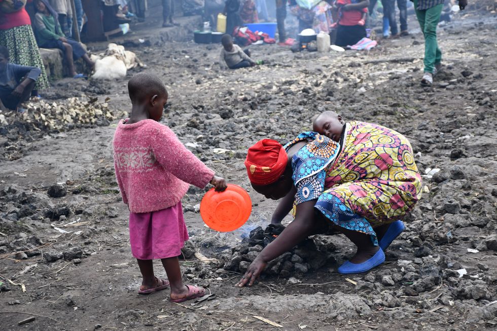 photo os a mother with a baby on her back and a toddler with a plate