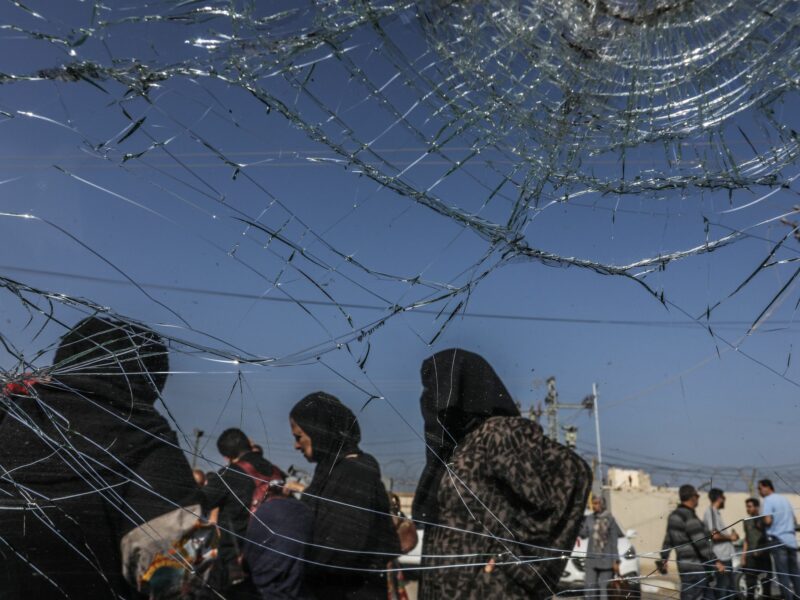 Photo shot through a cracked window showing people waiting at the Rafah border crossing between Gaza and Egypt.