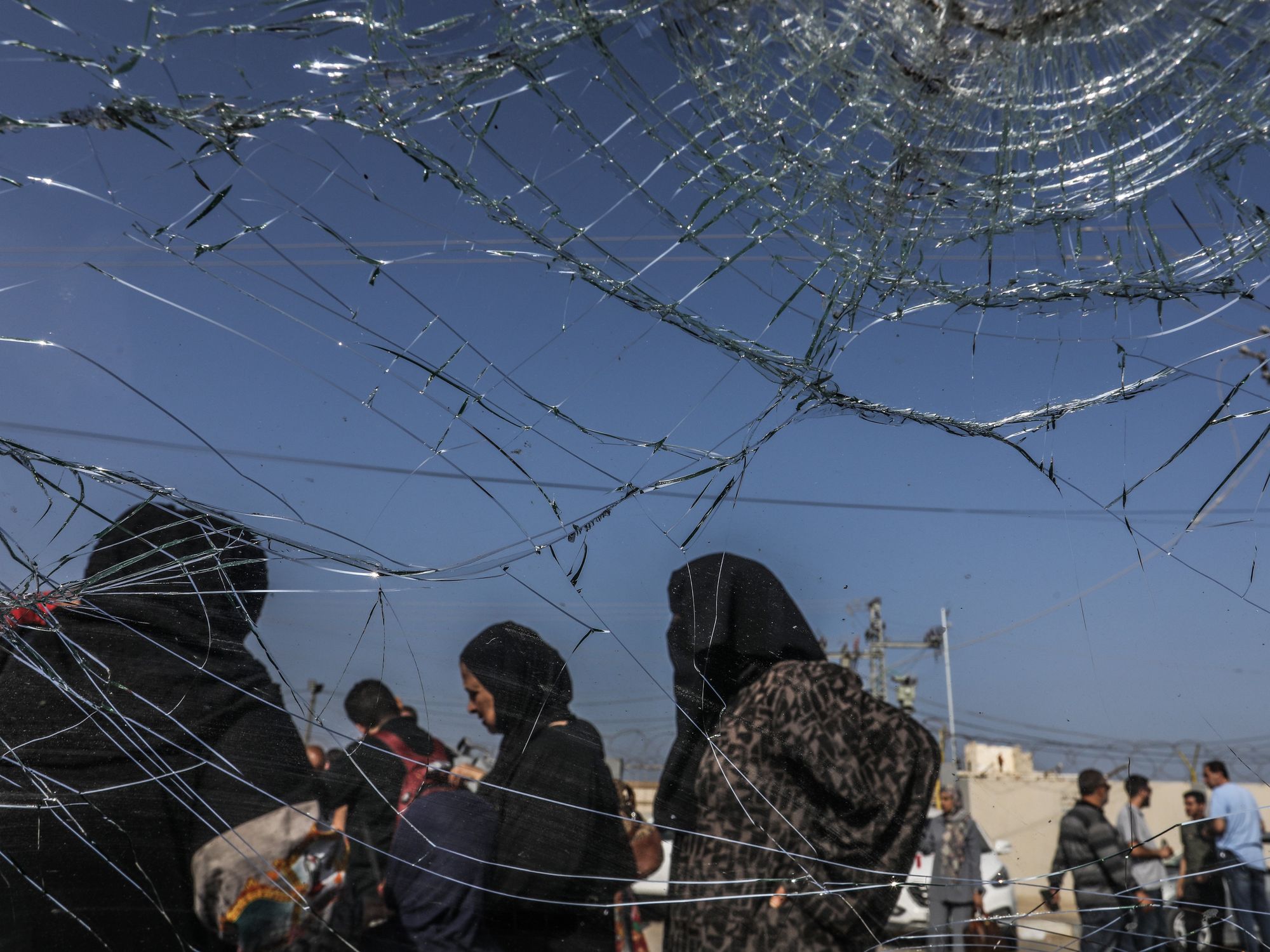 Photo shot through a cracked window showing people waiting at the Rafah border crossing between Gaza and Egypt.