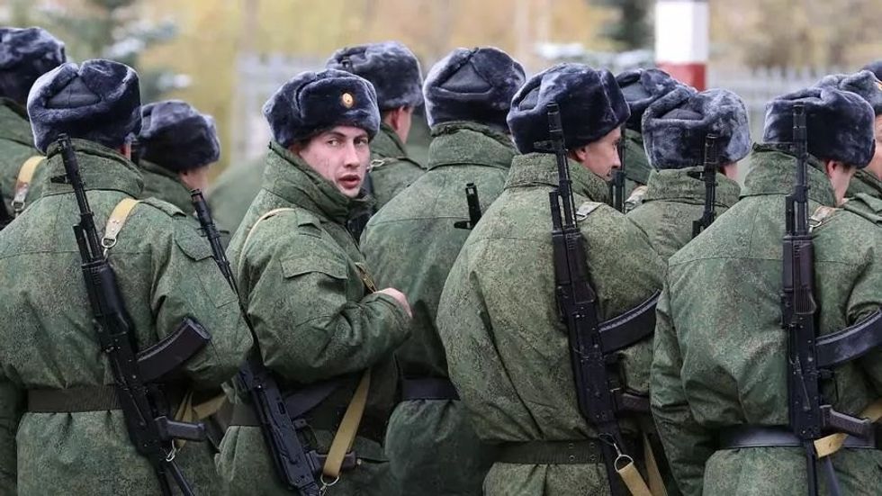 Photo showing a regiment of Russian soldiers marching forward, with one looking back