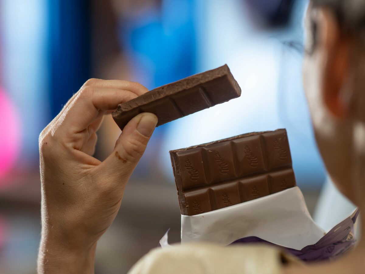 photo showing A woman holding a bar of chocolate in her hands in a living room in front of the TV.