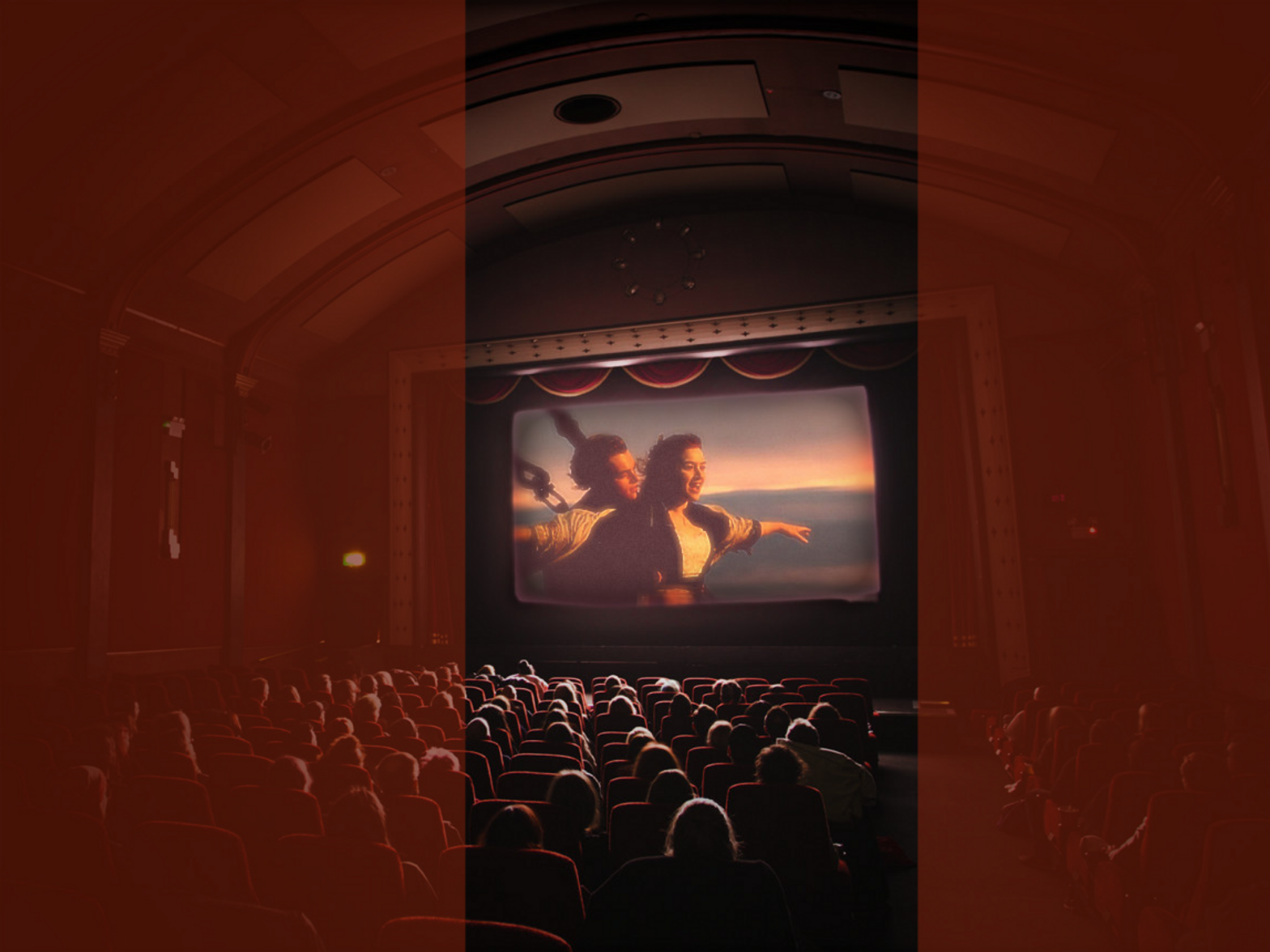 Photo showing an audience watching the iconic Titanic scene where the two lovers hold one another on the ship's helm.