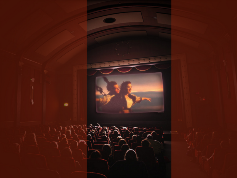 Photo showing an audience watching the iconic Titanic scene where the two lovers hold one another on the ship's helm.