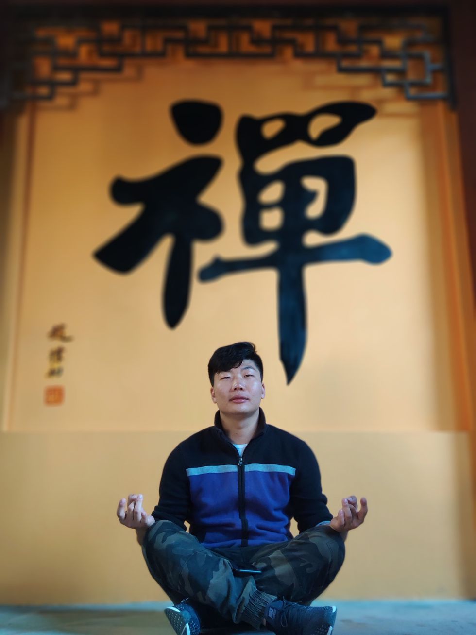 Photograph of a Chinese man sitting in a meditative prayer position at the West Wind Temple of Anhui Sheng, China.