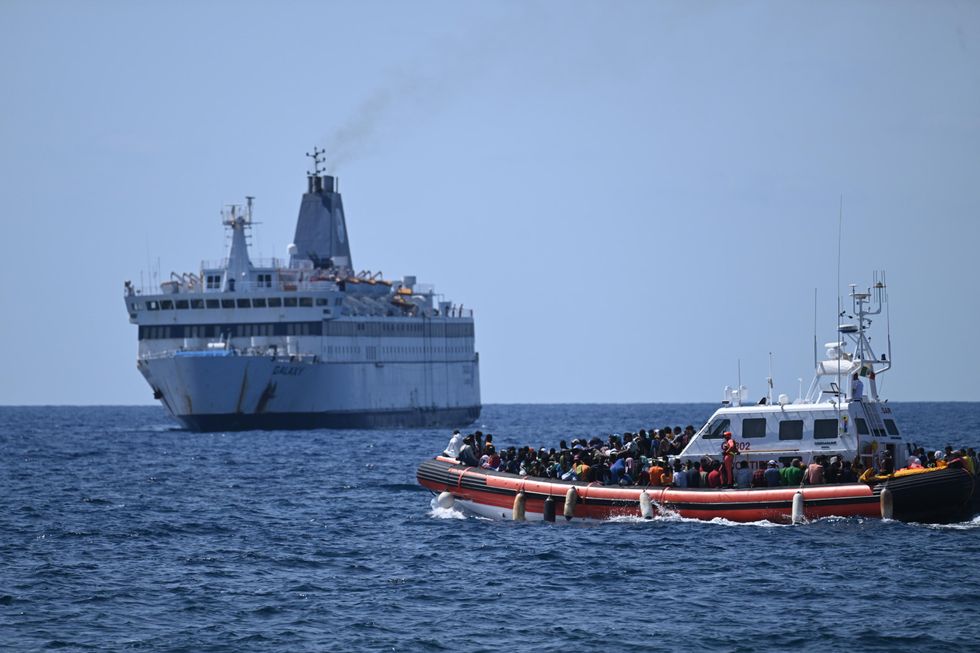 Photograph of a dinghy boat taking refugees from to a larger ferry which will transport them to the island of Lampedusa.