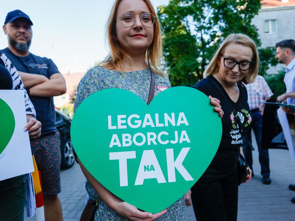 Photograph of a female protestor holding a green heart to fight against religious people who disrupt the proceedings of one of the few women-friendly public gynecology and obstetric wards in Poland.