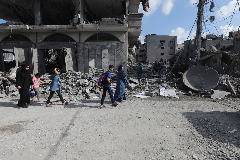 Photograph of a group of Palestinians inspecting a destroyed buildings following the Israeli airstrikes.
