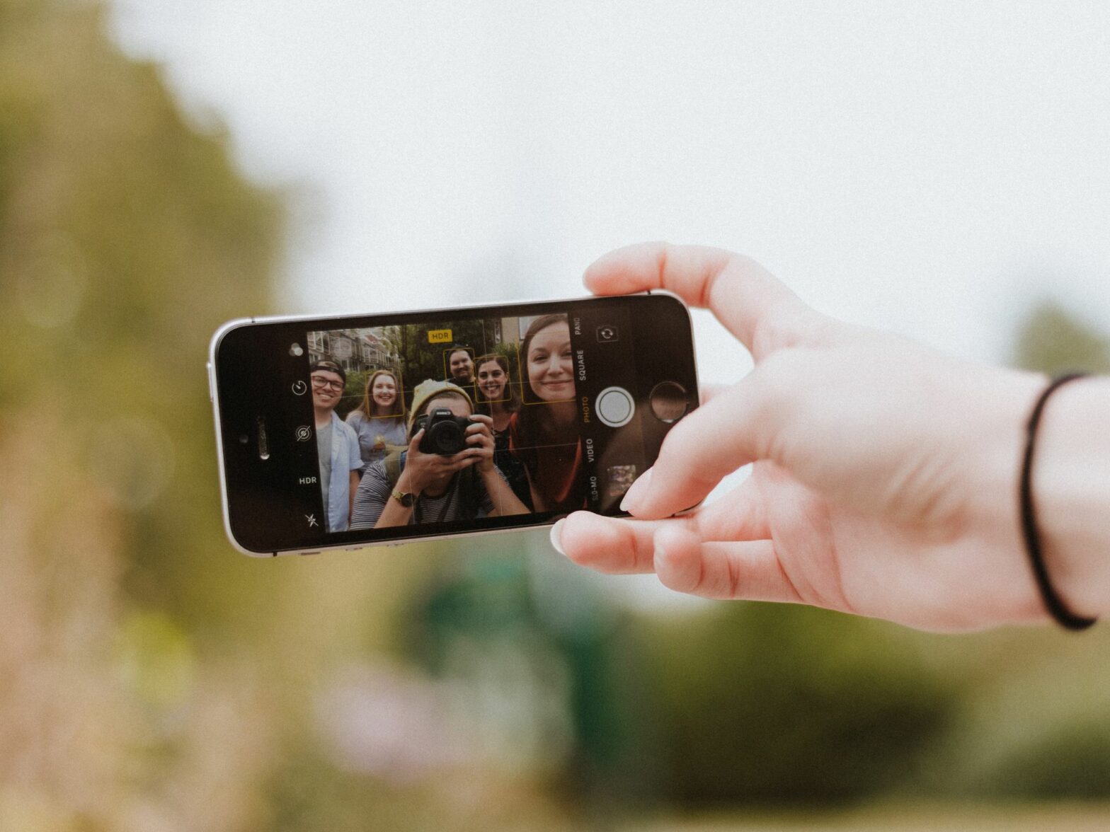 Photograph of a group of young people taking a selfie on an iPhone