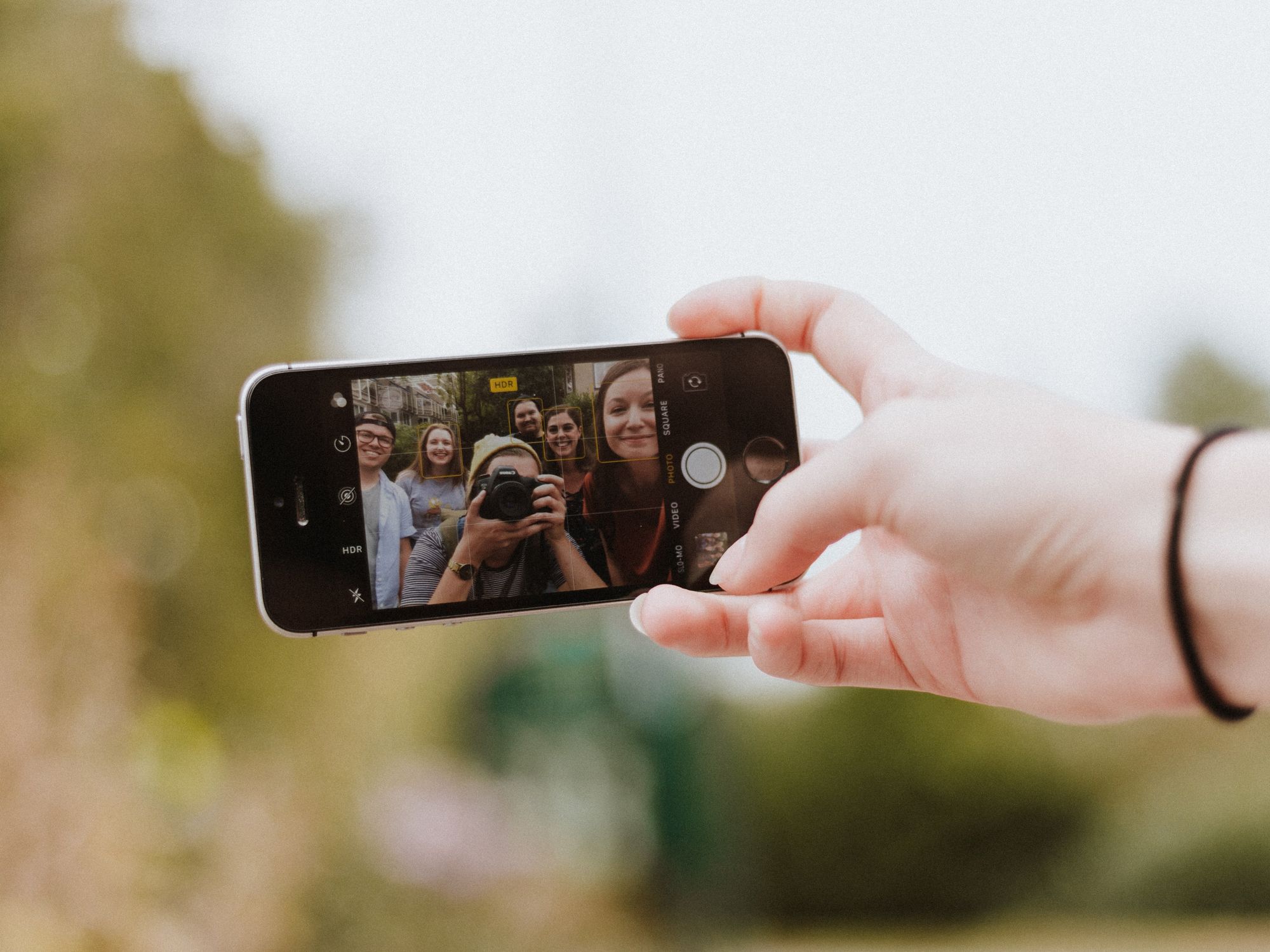 Photograph of a group of young people taking a selfie on an iPhone